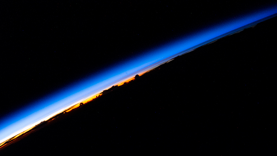 An orbital sunrise is pictured from the space station beaming across Earth's horizon revealing the silhouetted clouds above the South China Sea.