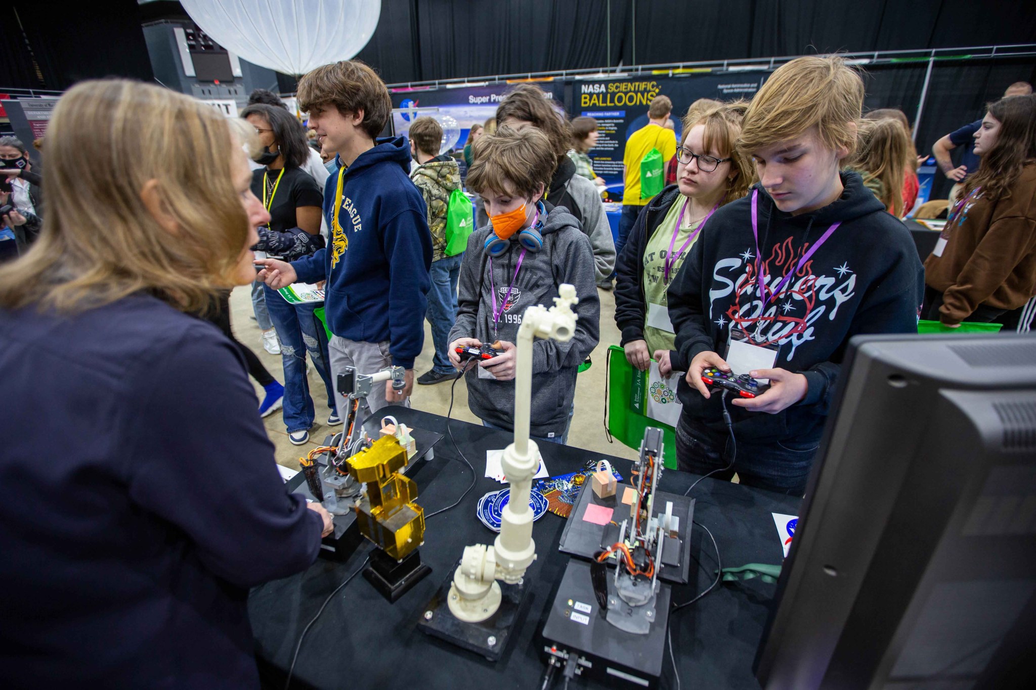 A white woman with blond hair talks to a group of middle-school children.