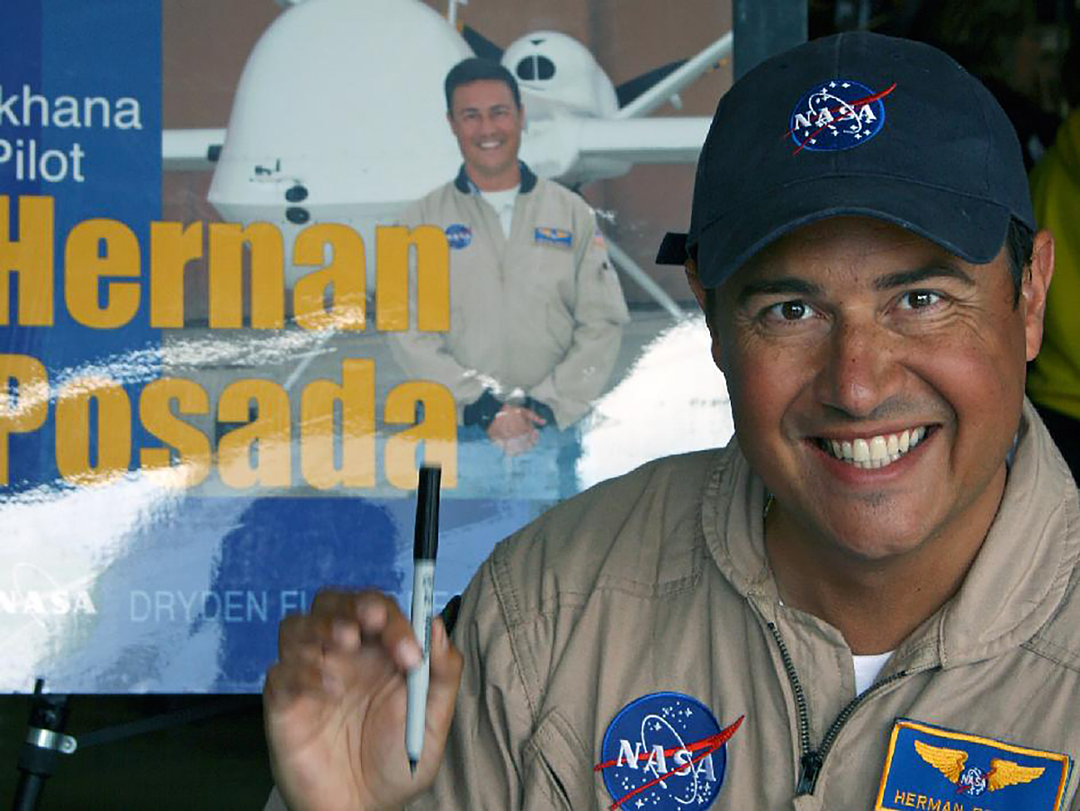 Hernan Posada, in front of display holding a marker.