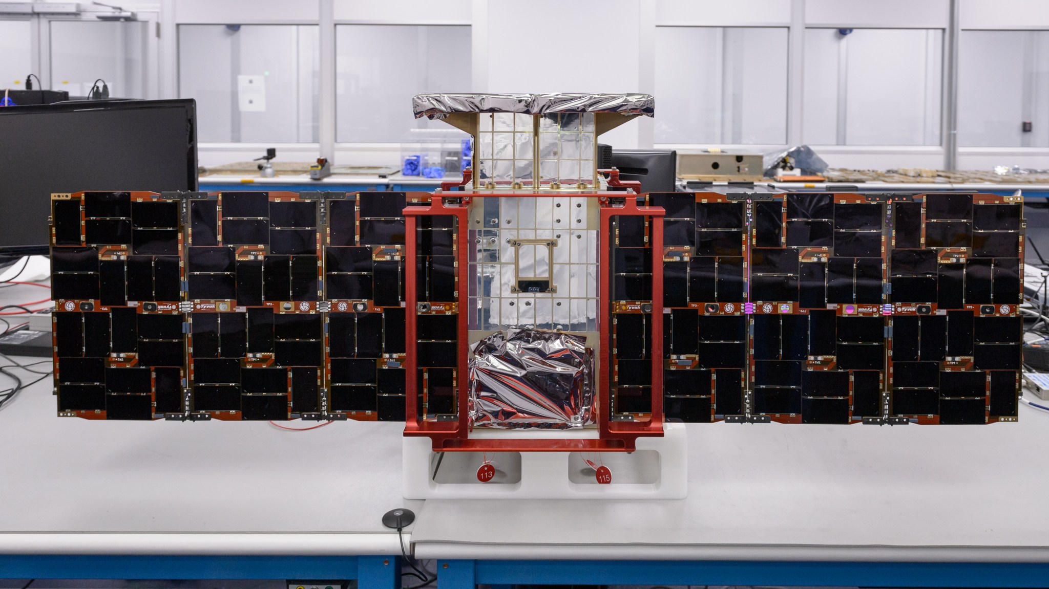 Photo of the CAPSTONE spacecraft with solar panels deployed on a workbench at Tyvak Nano-Satellite Systems, Inc., in Irvine, California.