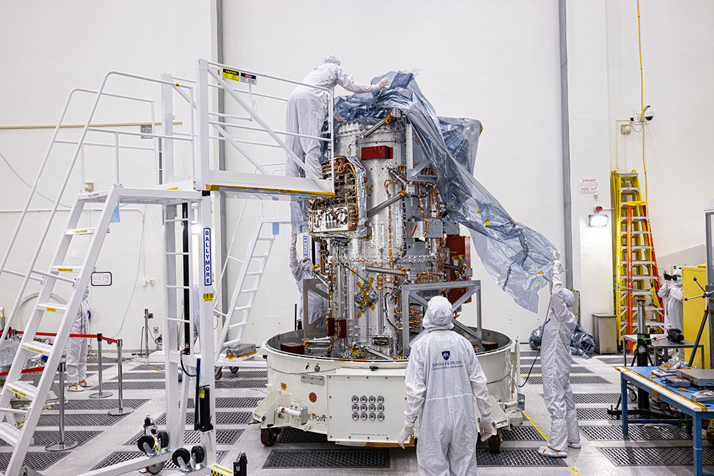 Engineers and technicians unwrap and inspect the main body of NASA’s Europa Clipper spacecraft