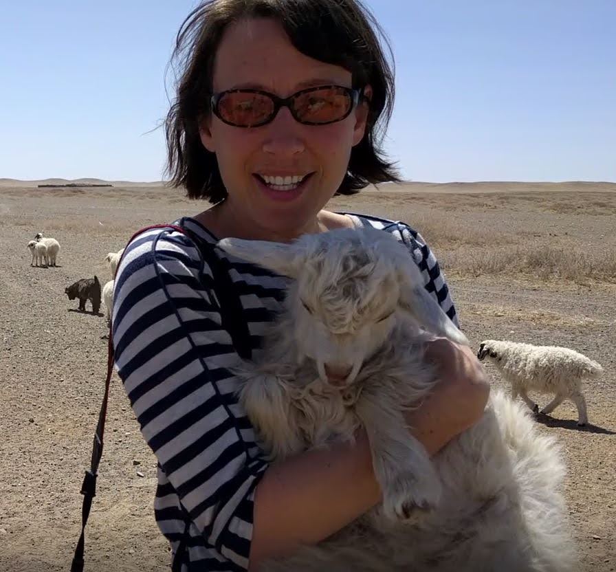 Photo of woman holding goat in Gobi desert