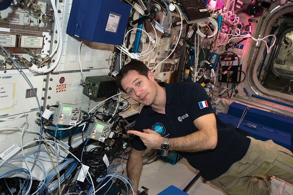 image of an astronaut posting next to payload hardware