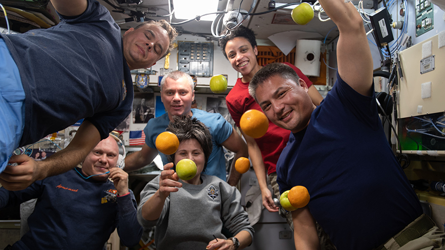 Expedition 67 crew members pose with fresh fruit delivered aboard the Progress 81 cargo craft on June 3, 2022.