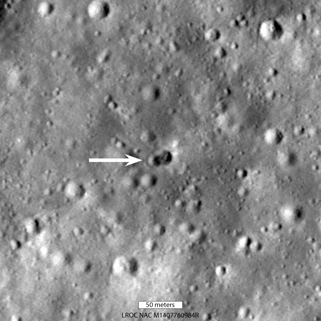 rocky, grayscale lunar landscape, as seen from above by LRO; a white arrow indicates the rocket body impact site