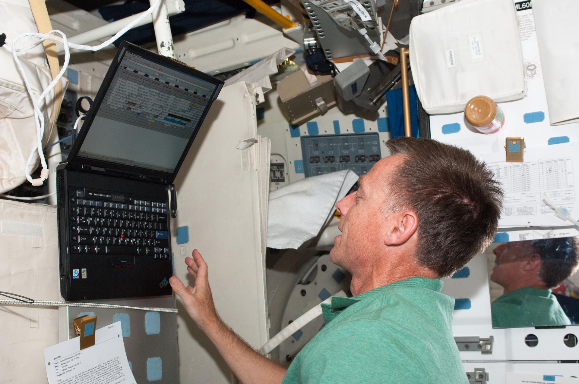 NASA astronaut Chris Ferguson, STS-135 commander, inputs data on a computer on Atlantis’ middeck on July 13, 2011, during the sixth day in space for him and three crewmates.