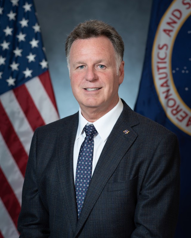 Portrait of Anthony Facca with U.S. and NASA Flags in background