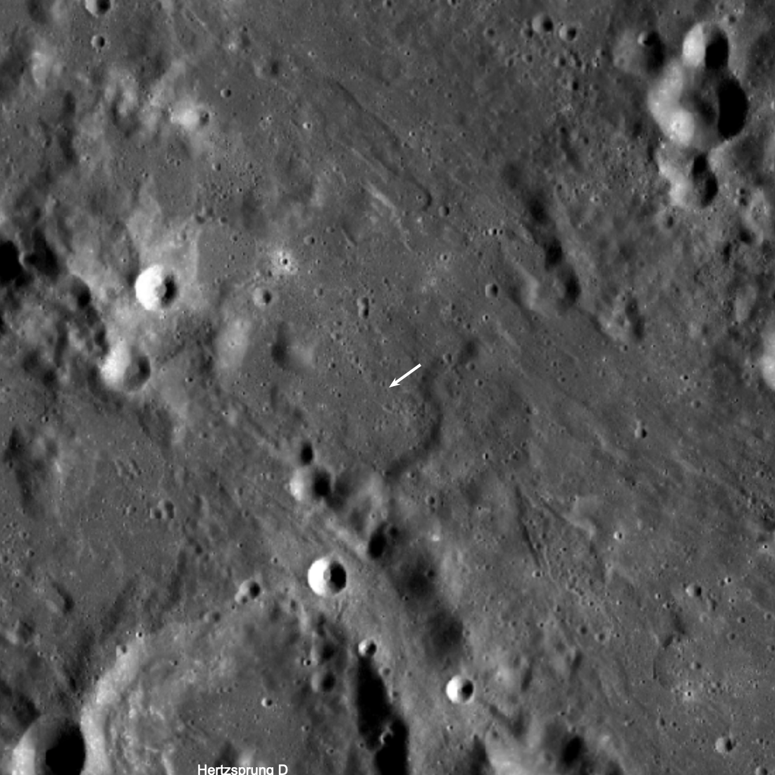 rocky, grayscale lunar landscape, as seen from above by LRO; a white arrow indicates the rocket body impact site