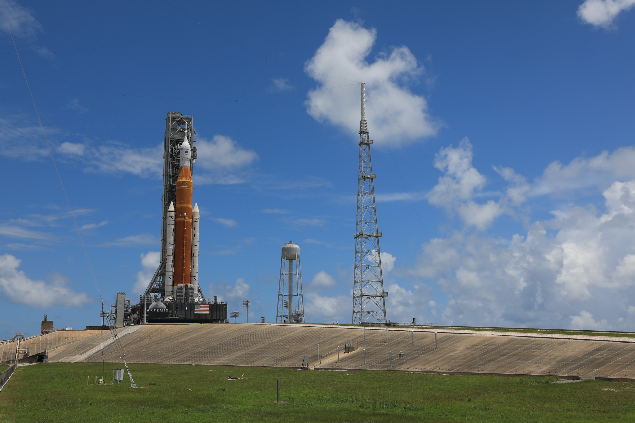 A brilliant blue sky serves as a backdrop for the Artemis I Space Launch System (SLS) and Orion spacecraft atop the mobile launcher at Launch Pad 39B at NASA’s Kennedy Space Center in Florida on June 30, 2022.
