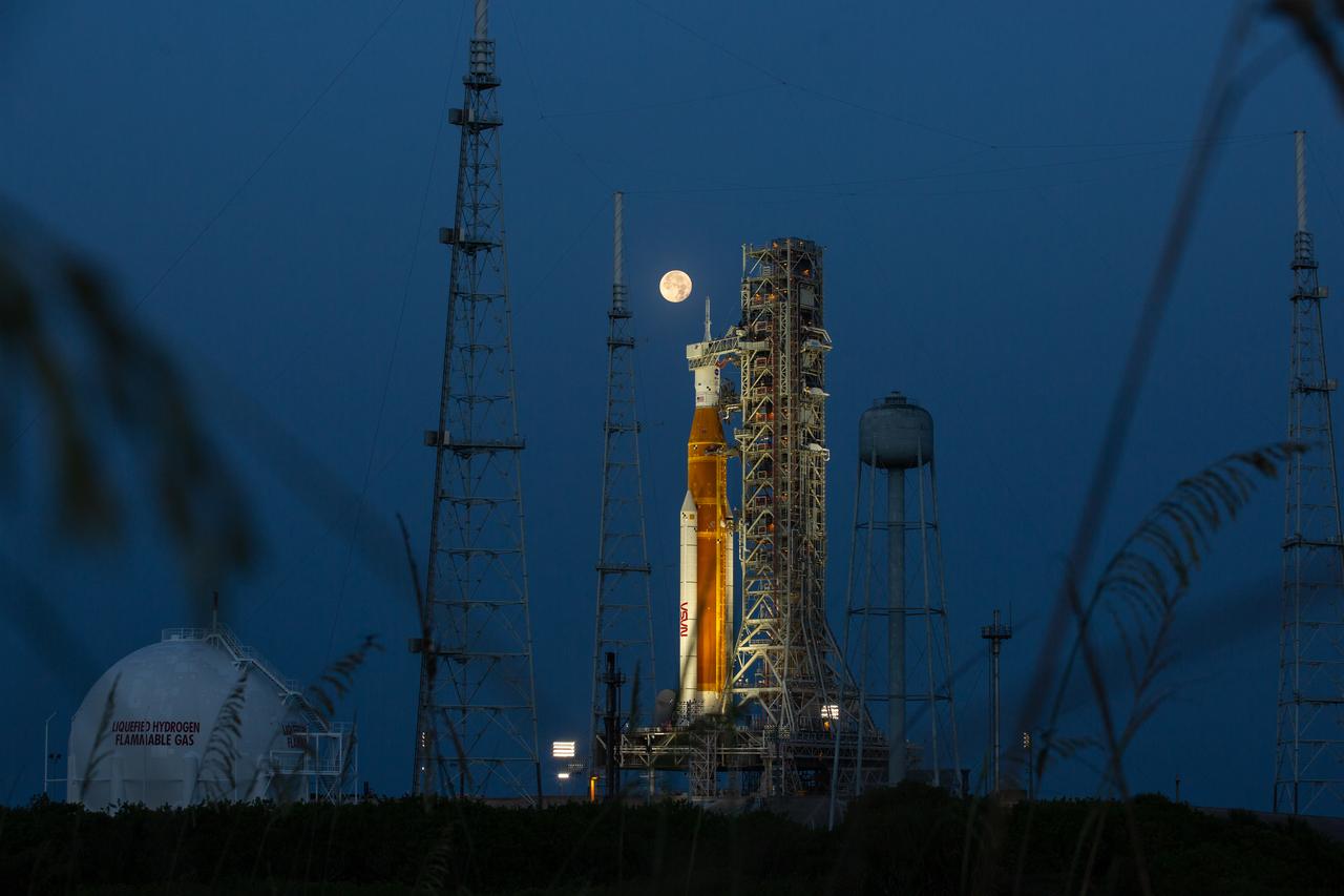 A full Moon is in view from Launch Complex 39B at NASA’s Kennedy Space Center in Florida on June 14, 2022 with the Artemis I Space Launch System (SLS) and Orion spacecraft, atop the mobile launcher. 