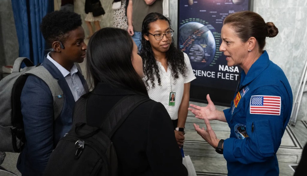 Astronaut talking to three young adults