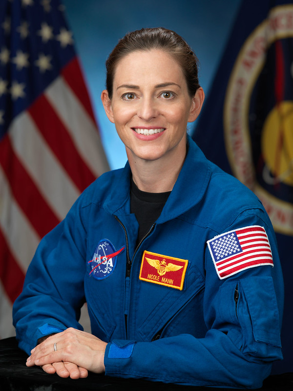 A smiling female astronaut in a blue jump suit