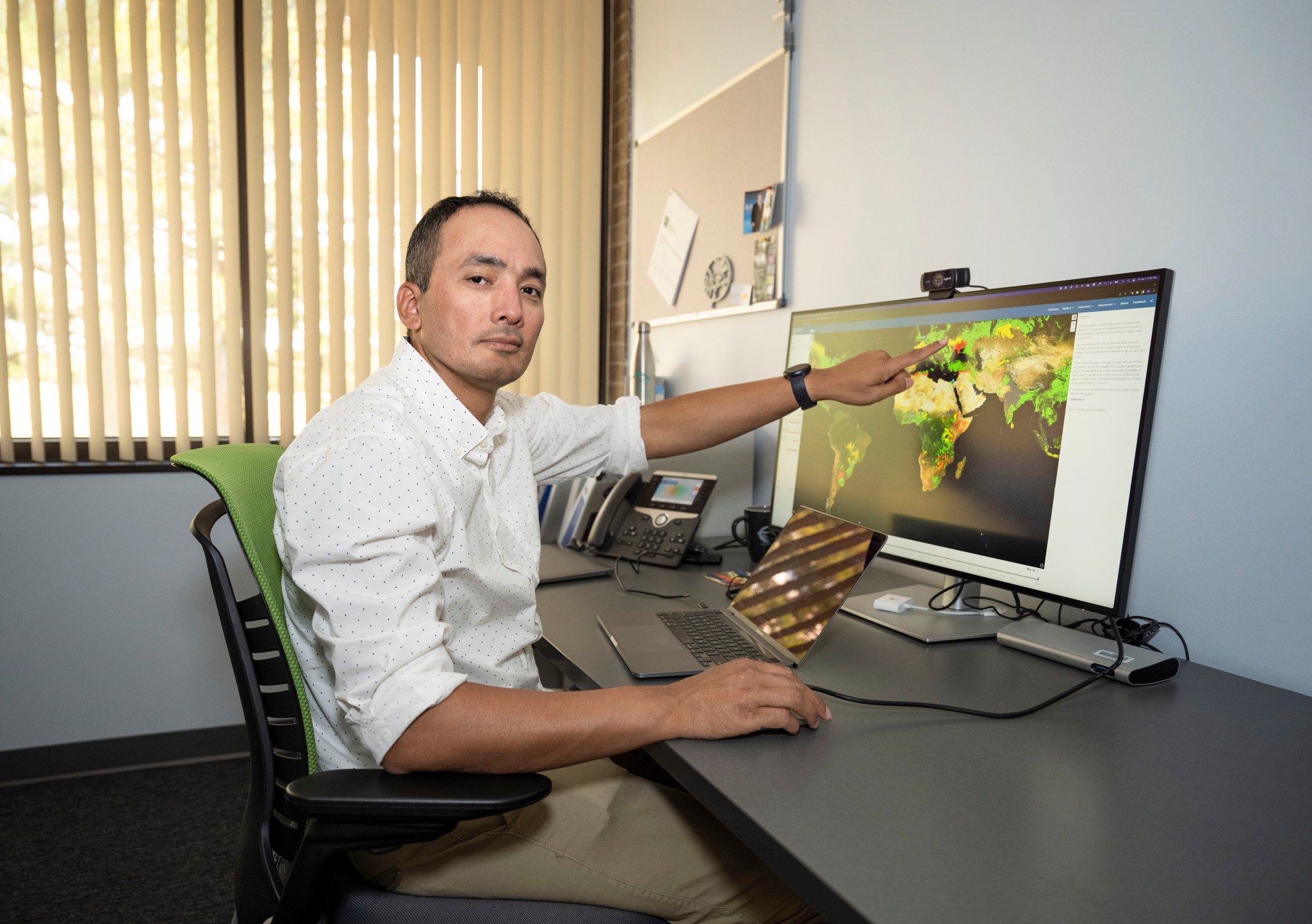 Dr. Manil Maskey, a data scientist at NASA’s Marshall Space Flight Center, is sitting at his desk showing the Earth Observing Dashboard on his computer.