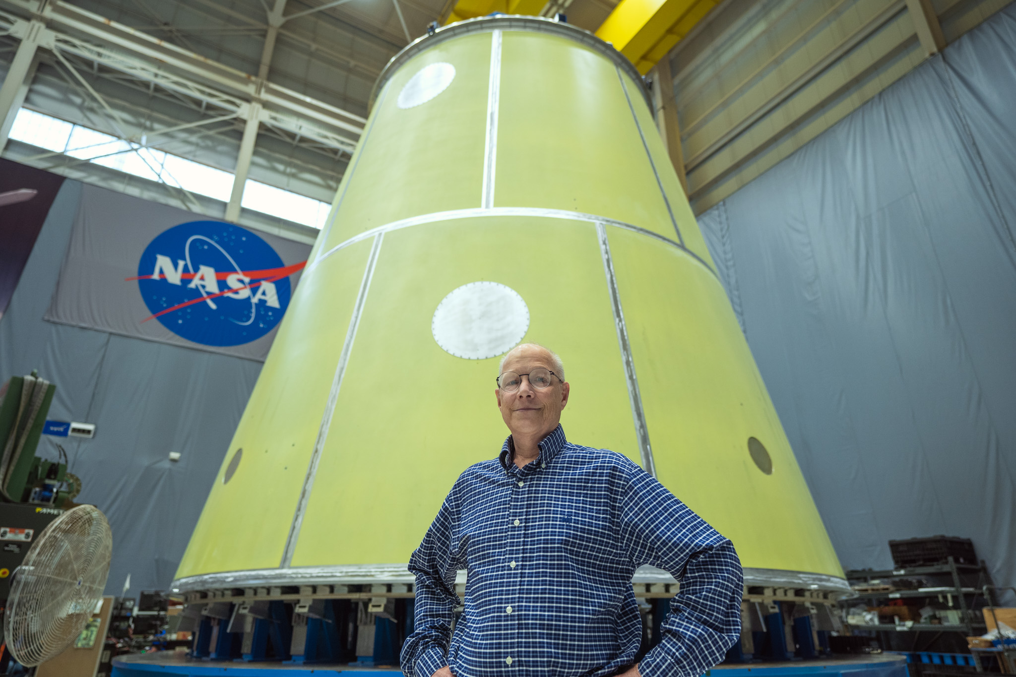 Andy Schorr stands in front of SLS hardware with the NASA logo behind him.