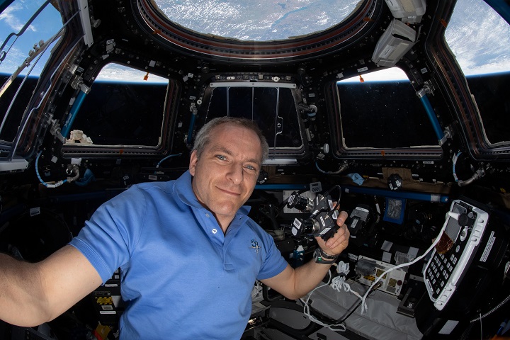 image of an astronaut holding a camera inside the cupola in the station