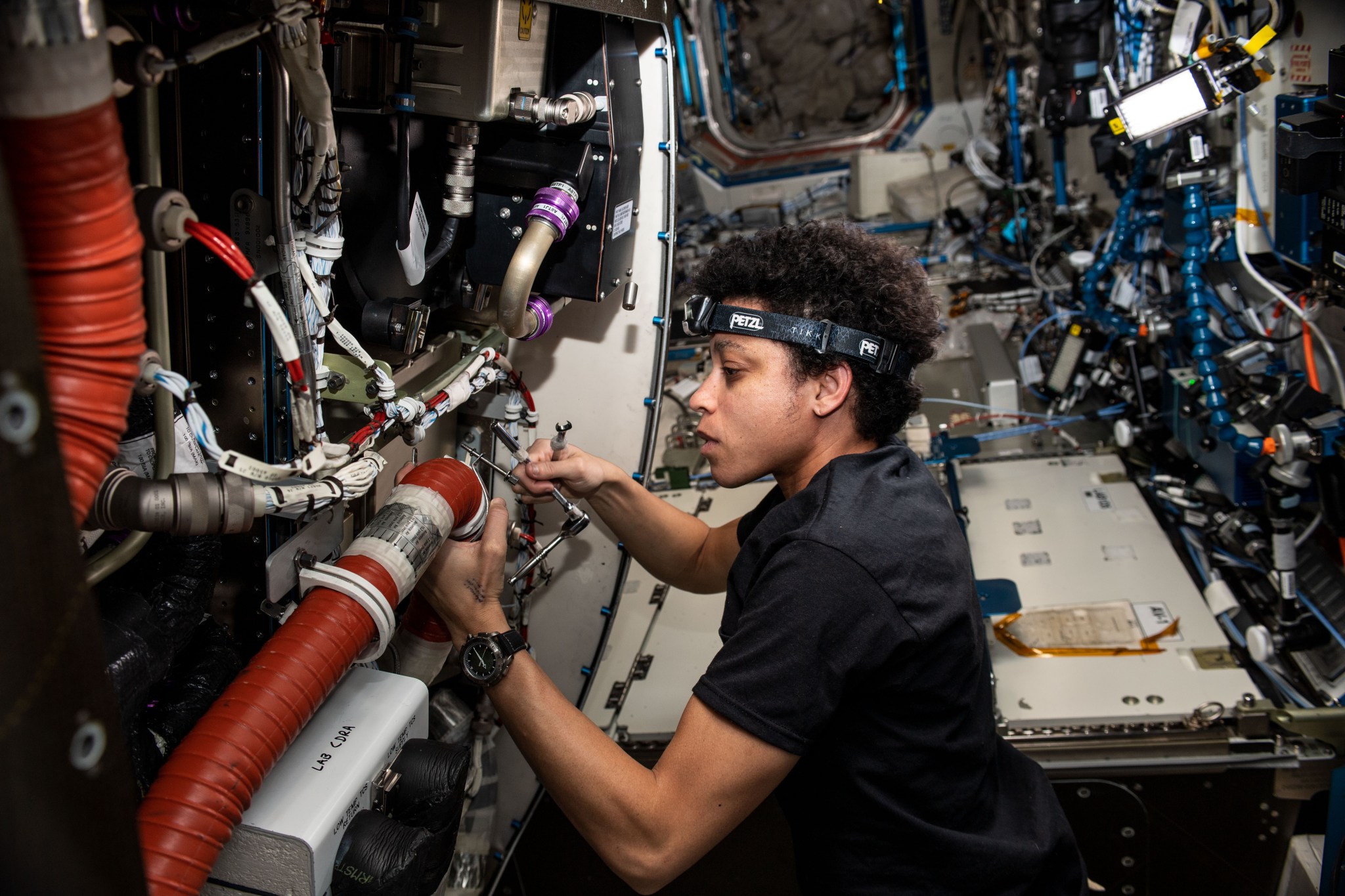 NASA astronaut Jessica Watkins replaces components on the Major Constituents Analyzer, a life support device in the U.S. Destiny laboratory module, that ensures oxygen and carbon dioxide levels remain safe aboard the International Space Station.