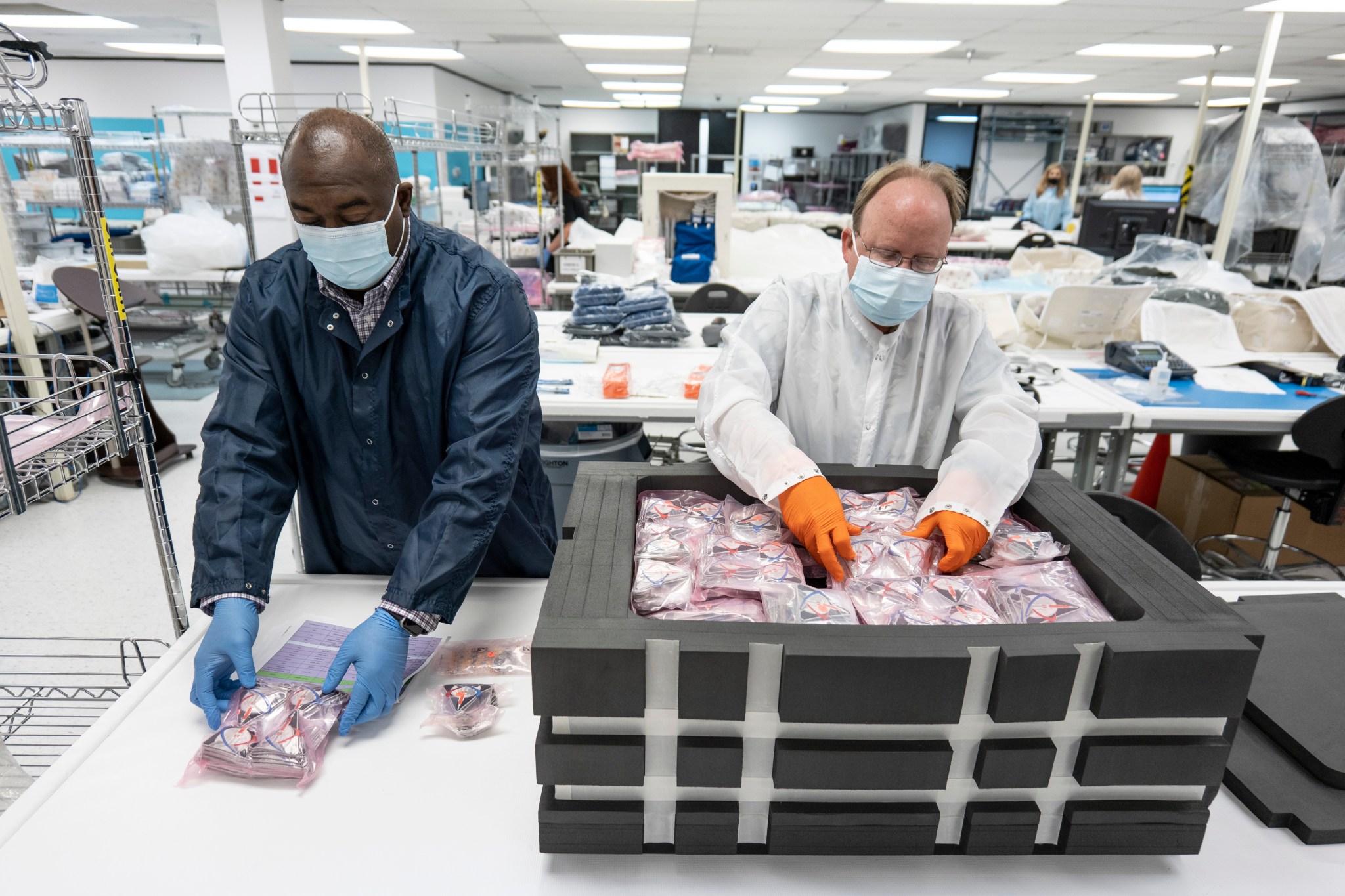 Two employees examine Artemis I patches to be included in the Official Flight Kit for the mission.