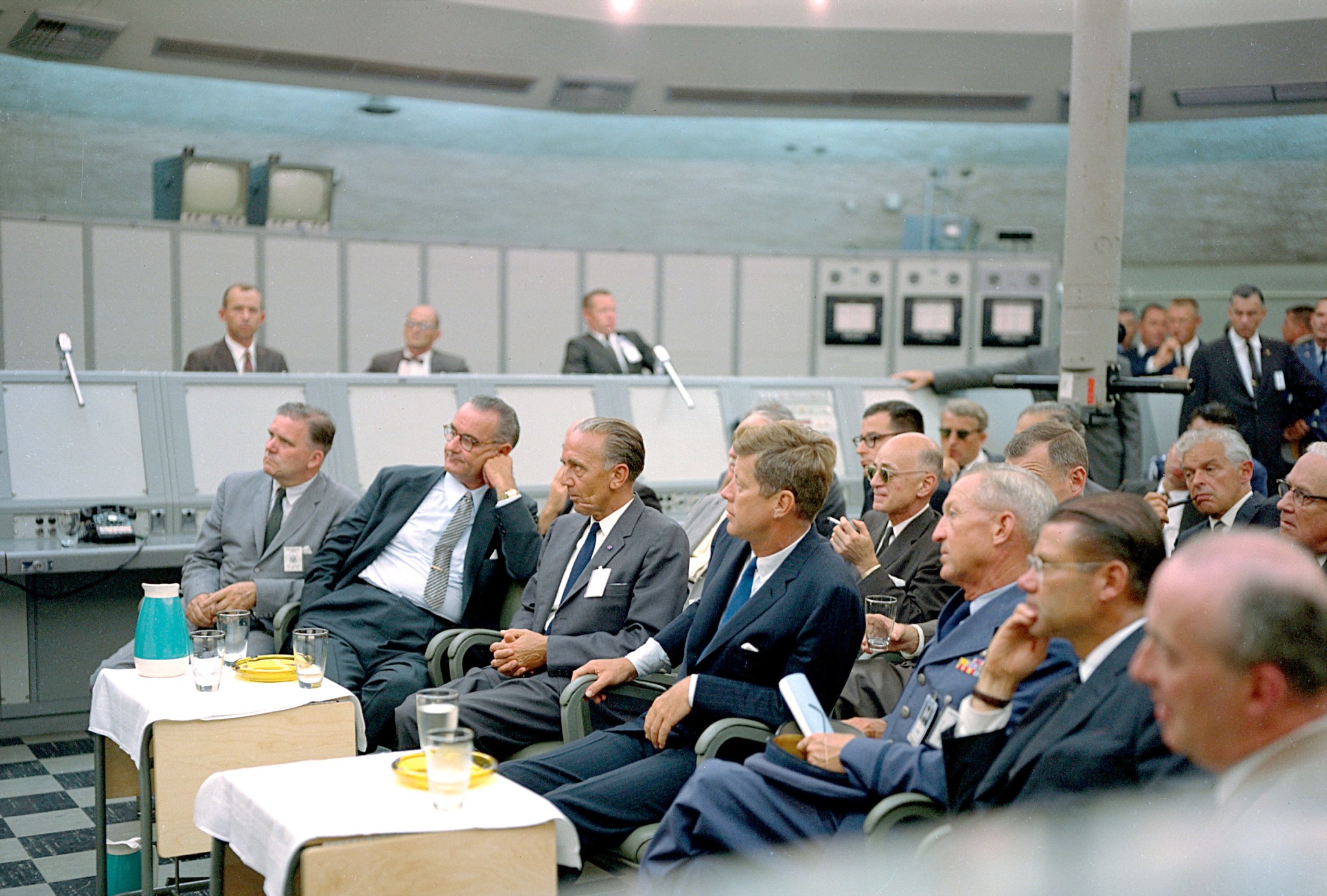 A group of men listen to a presentation at the blockhouse of Launch Complex 34 at the Cape Canaveral Missile Test Annex in Florida. Seated, from the left, are NASA Administrator James E. Webb, Vice President Lyndon B. Johnson, Launch Operations Center Director Kurt H. Debus and President John F. Kennedy.
