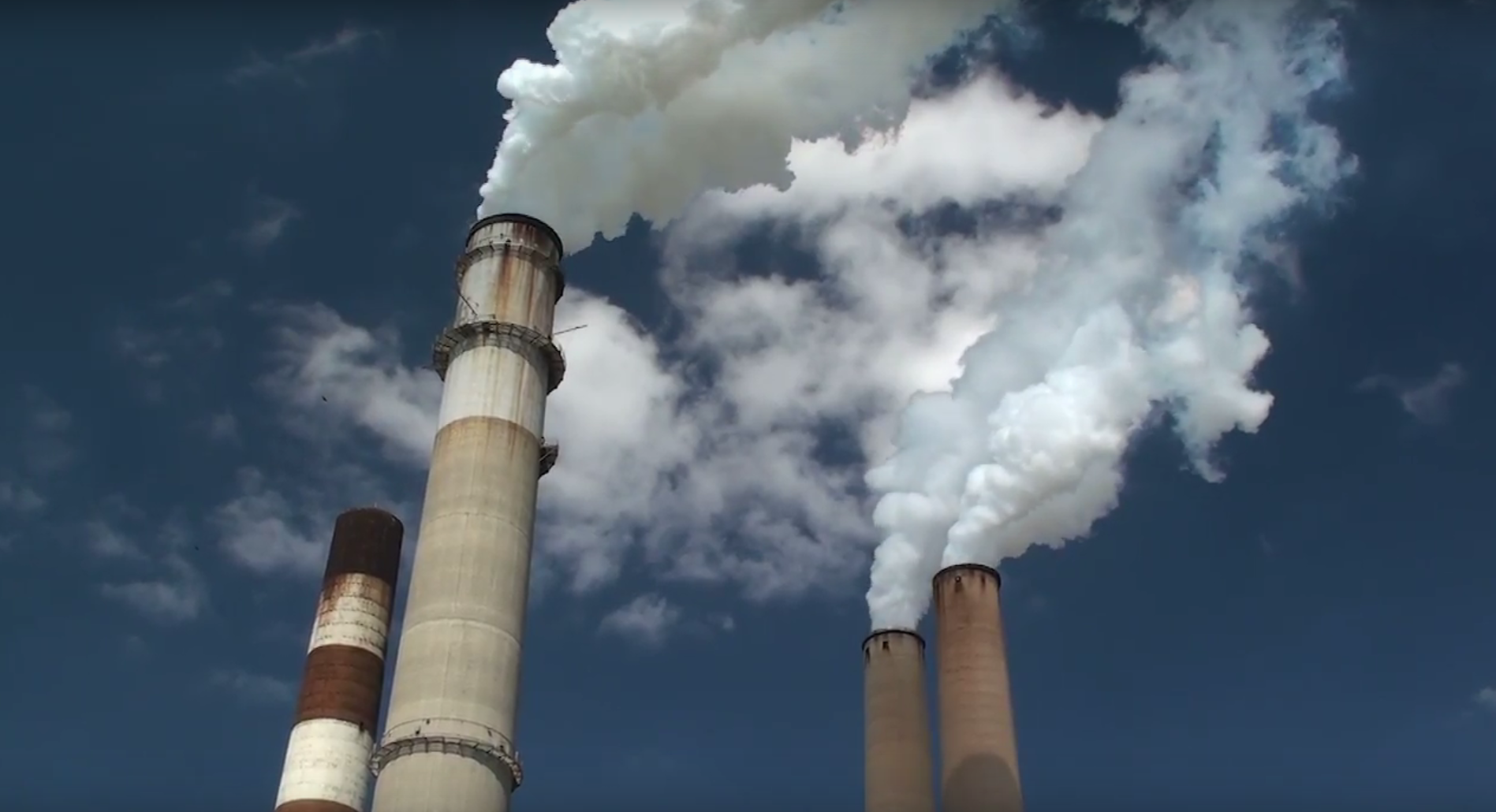 photo of smokestacks with clouds coming out of them