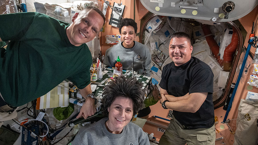 (Clockwise from left) Astronauts Bob Hines, Jessica Watkins, Kjell Lindgren, and Samantha Cristoforetti pose for a portrait during dinner time in the space station's Unity module.