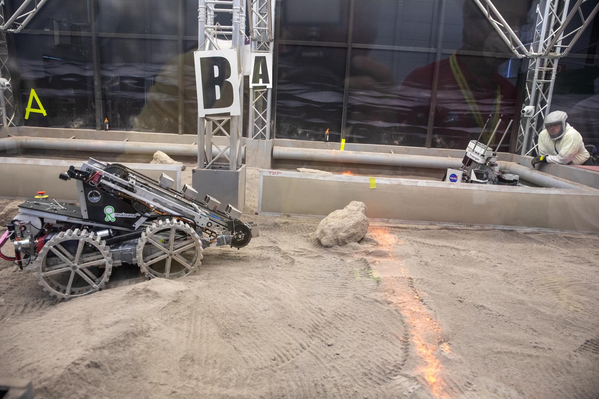 A robotic miner from Marquette University in Milwaukee, Wisconsin, prepares to dig in the mining arena during NASA’s LUNABOTICS competition on May 27, 2022, at the Center for Space Education near the Kennedy Space Center Visitor Complex in Florida. 