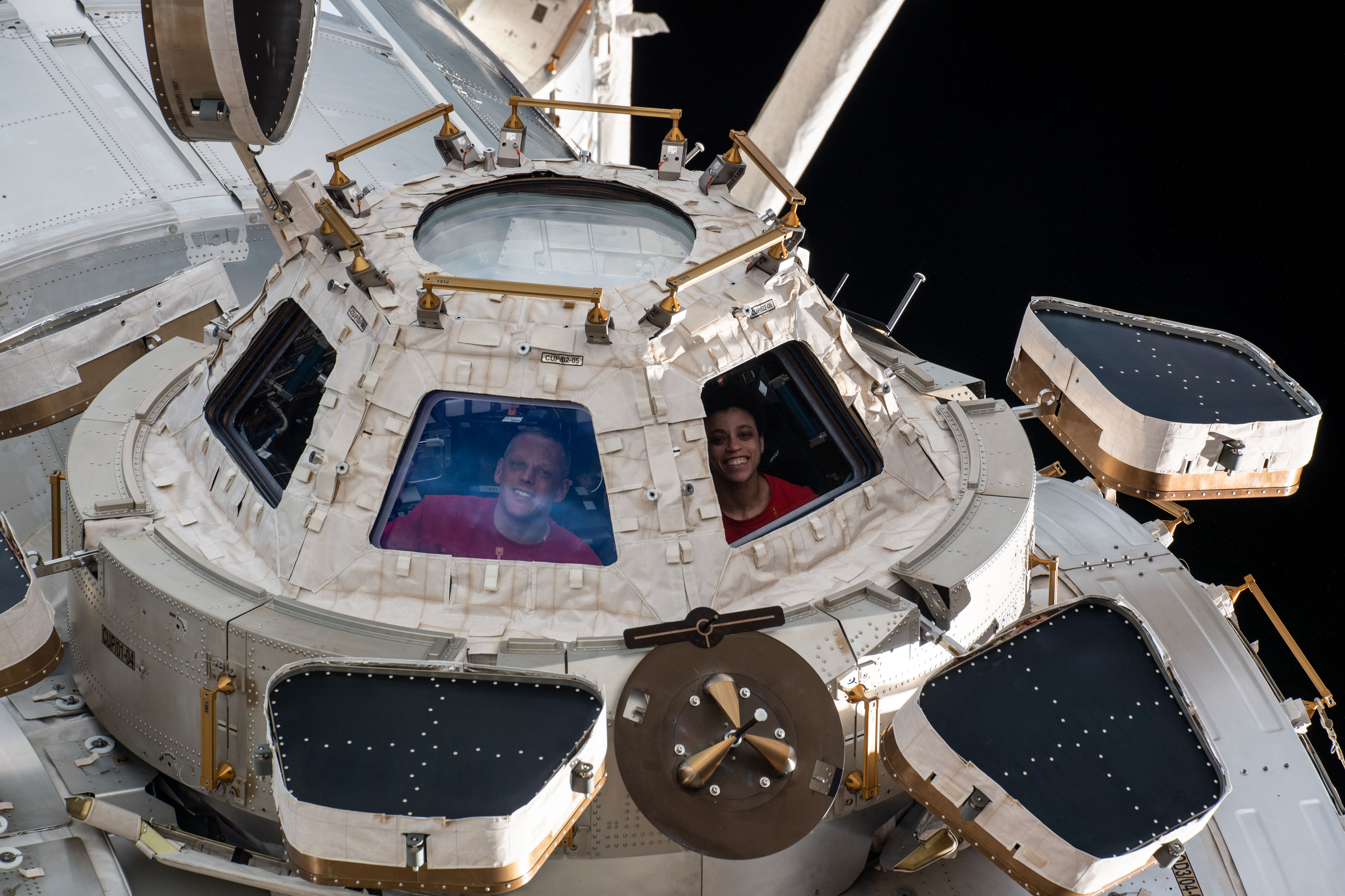 NASA astronauts Bob Hines and Jessica Watkins look out from a window on the space station’s cupola
