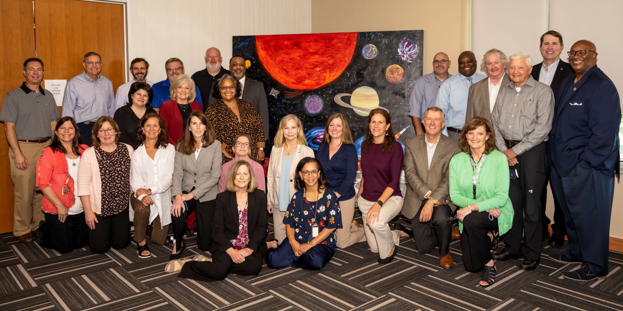 Members of Marshall Space Flight Center’s senior leadership stand in front of the painting they created during a team-building exercise at an offsite event this summer. 