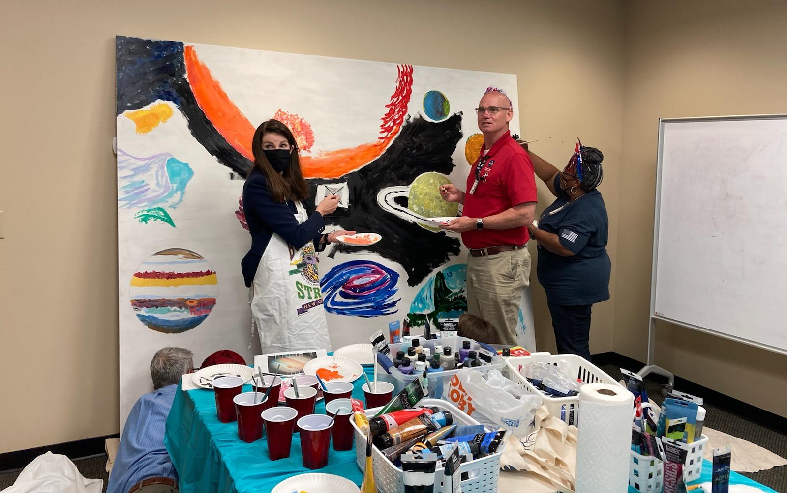 Members of Marshall’s senior leadership add colorful touches to a canvas painting during an offsite retreat this summer. 