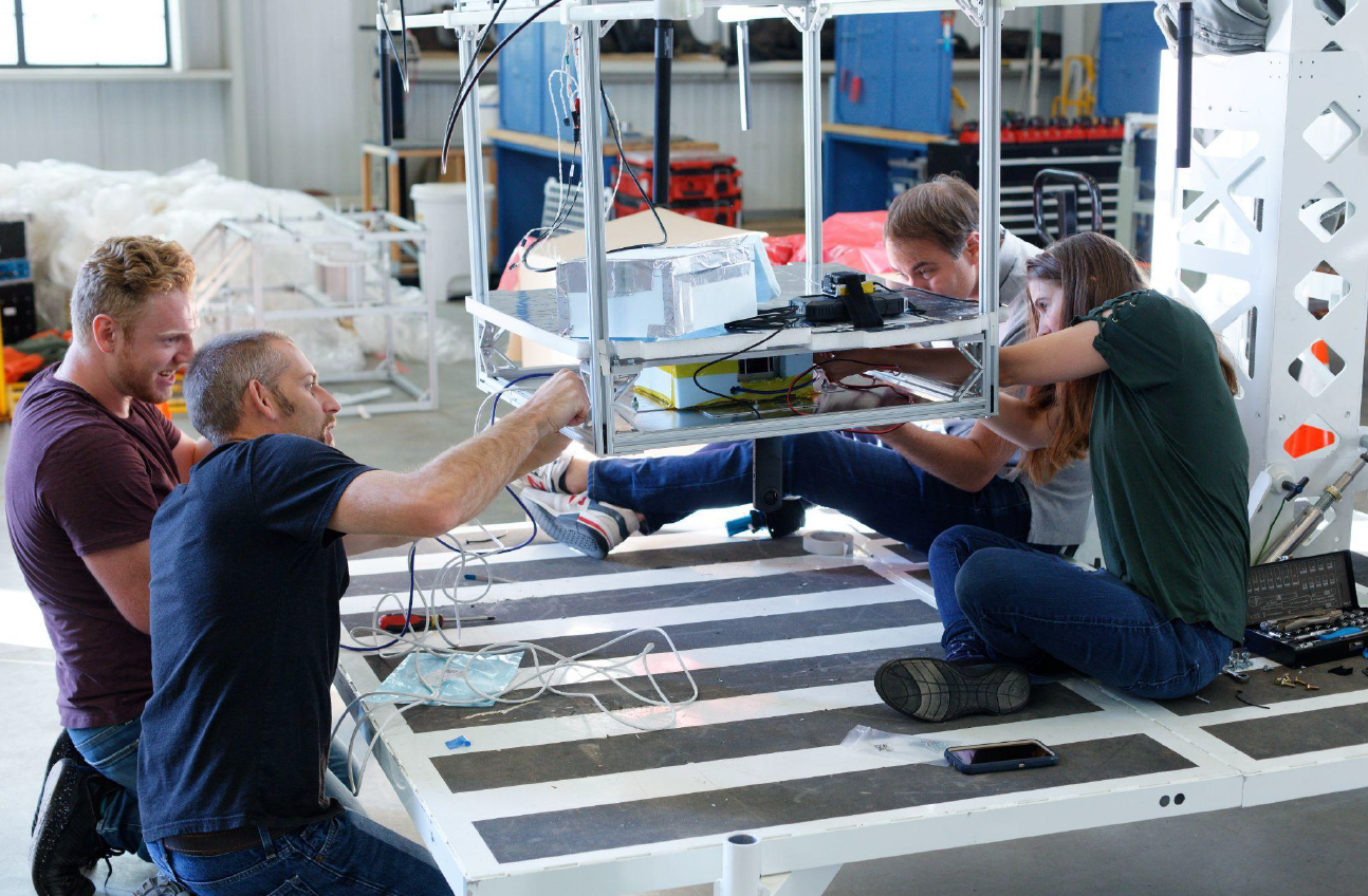 Flight integration: Aerostar’s Eric Ramsey and Kelly Banghart work with Orion Labs’ Kolbron Schoenberger and Sara Jennings to integrate the Quantum Earth Observation payload onto the high-altitude balloon’s gondola prior to launch.