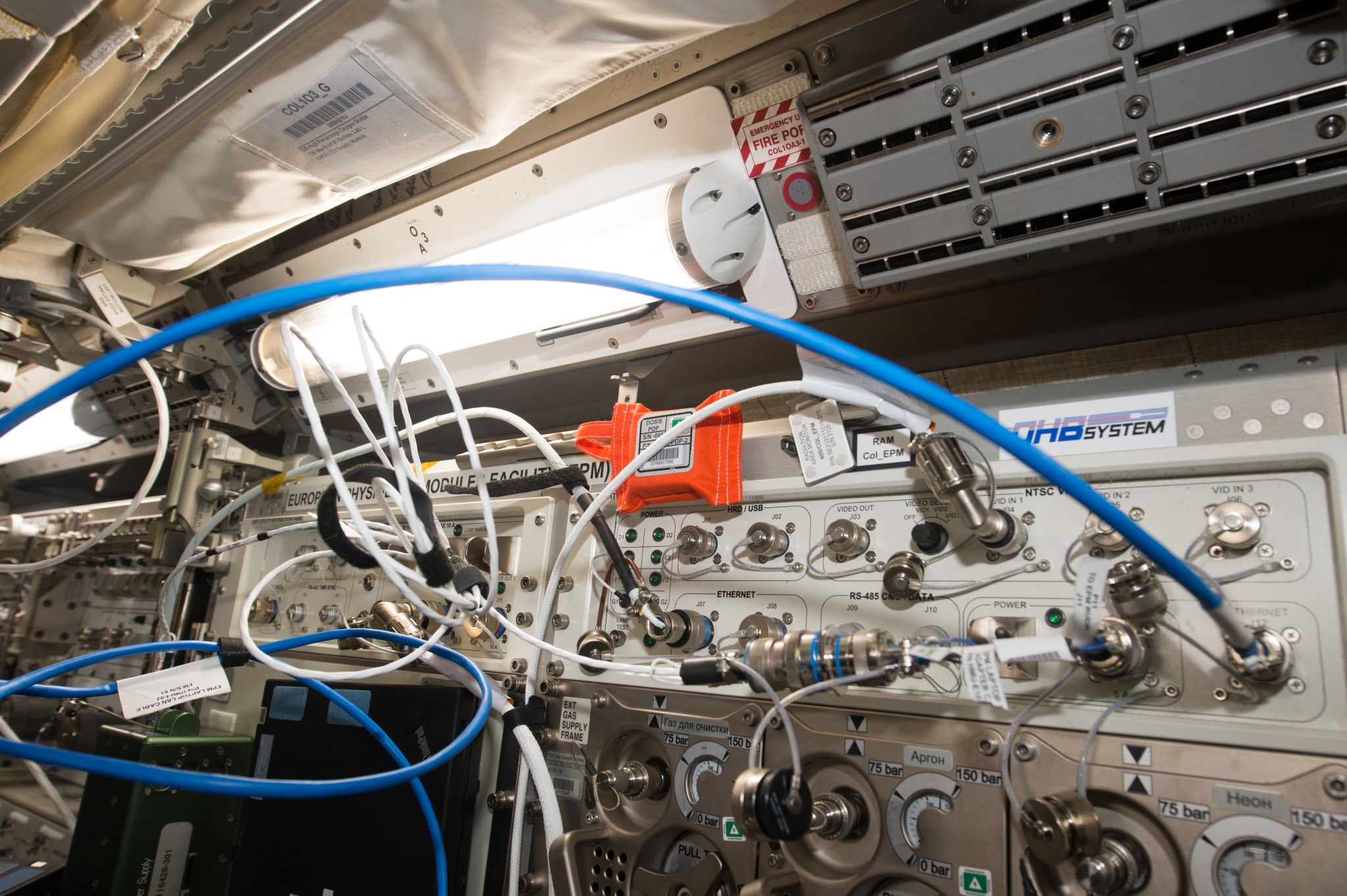 image of a bright orange sensor and experiment hardware in a rack of the space station module