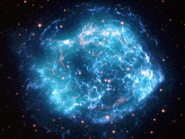 Composite images of the Cas A supernova remnant that looks like a spherical cloud resembles a hazy ball of turquoise and neon blue lightning, marbled with veins of gold.