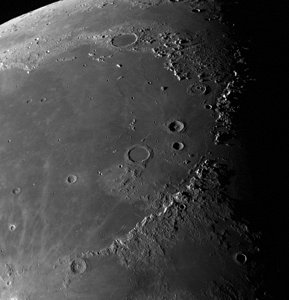 A close-up shot of the Moon's surface, with craters and craggy mountains curving across the right side of the image, which fades to black.