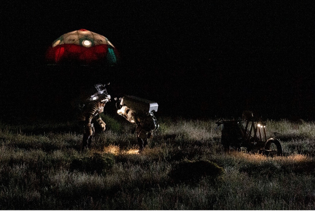 Nighttime photo of NASA astronauts Zena Cardman and Drew Feustel inspect an interesting geologic outcrop while lunar lighting shadows are being simulated by a lighting cart system.