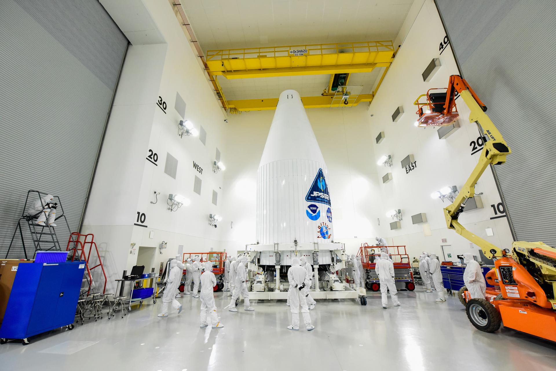 Technicians check the ULA Atlas V payload fairing containing NOAA's JPSS-2 satellite inside the Astrotech Space Operations Facility at Vandenberg Space Force Base.