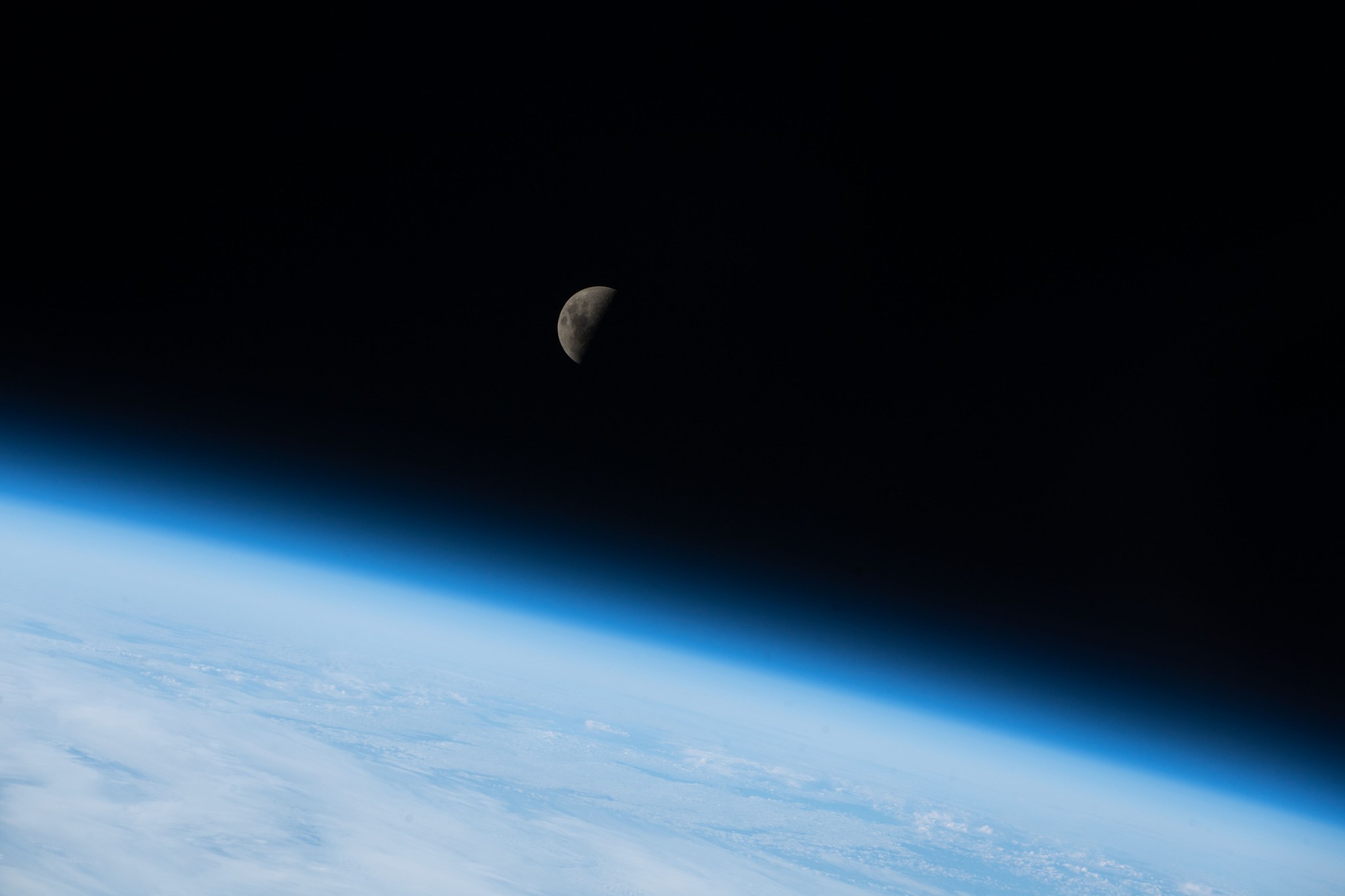 A quarter Moon is visible above Earth's horizon in this image taken as the ISS orbits 268 miles above the Indian Ocean south of Australia. 
