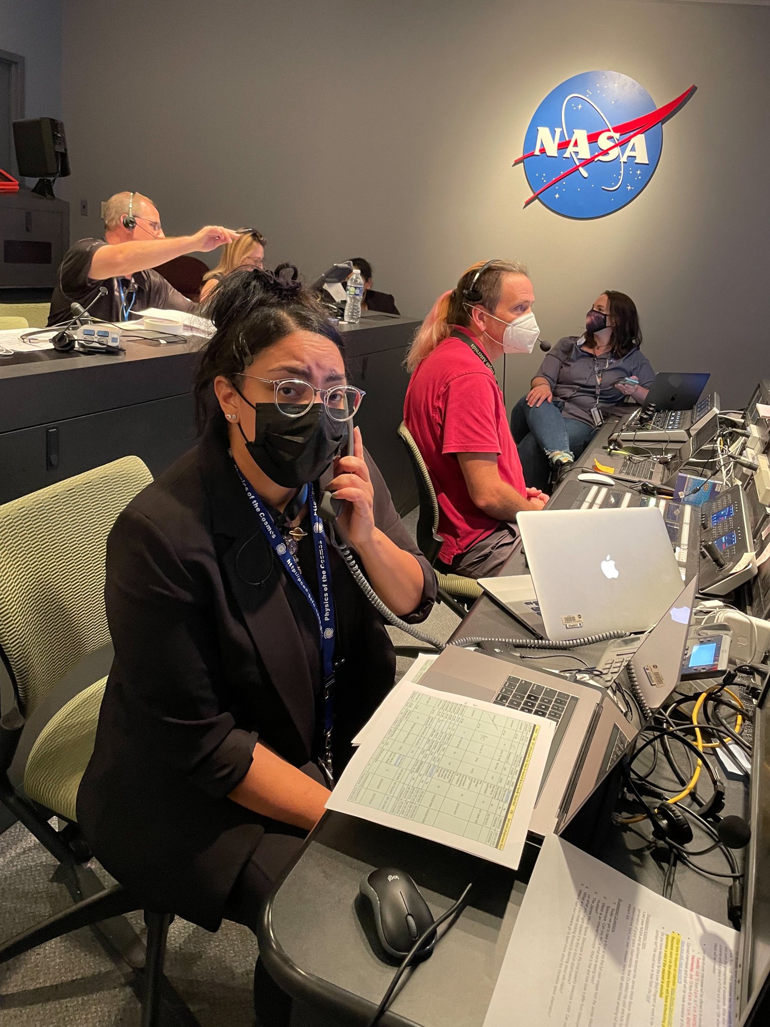 Rose Ferreira holds a telephone, seated among others in a broadcast control room.