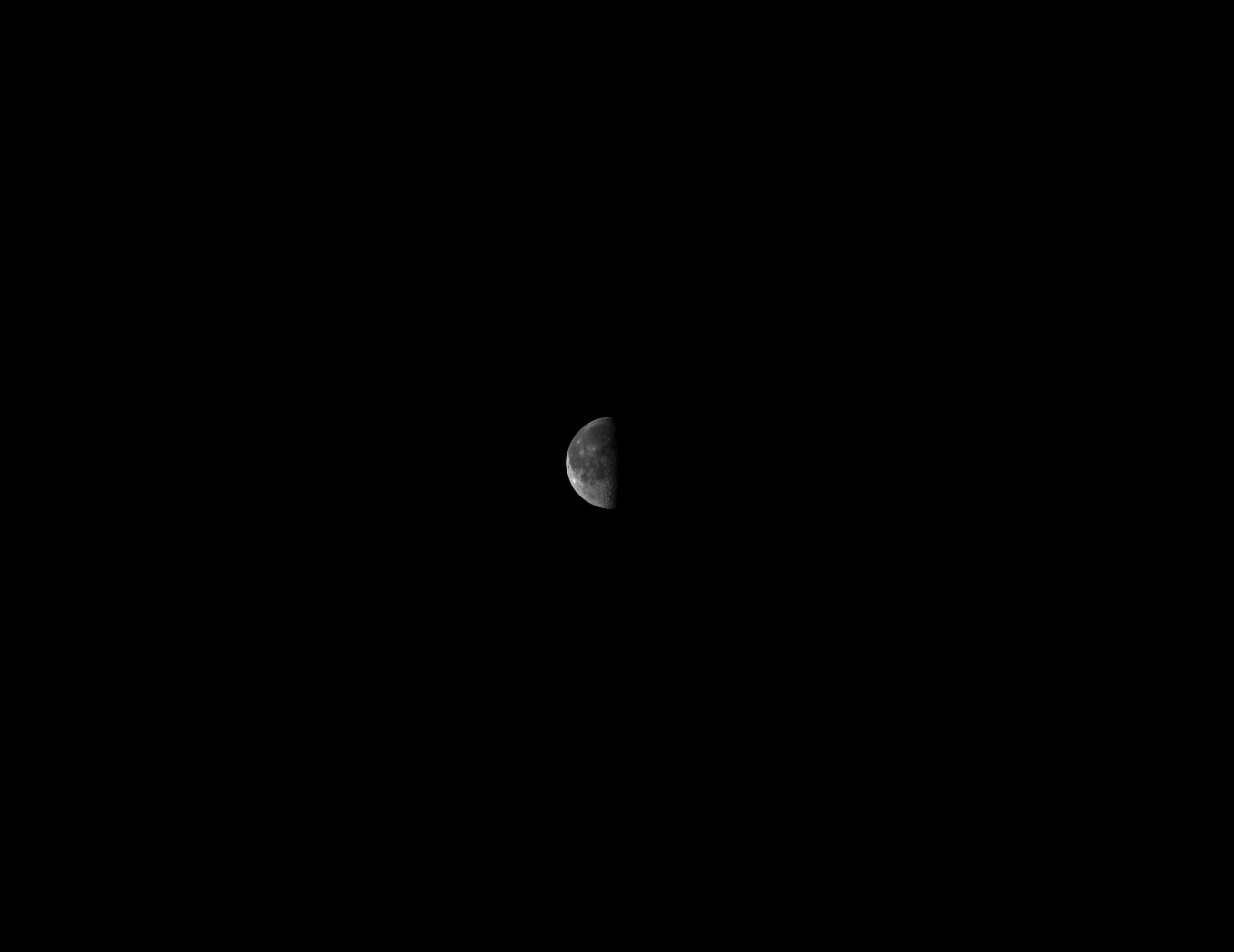 The moon seen from a far away distance, with the right side of the moon shaded.