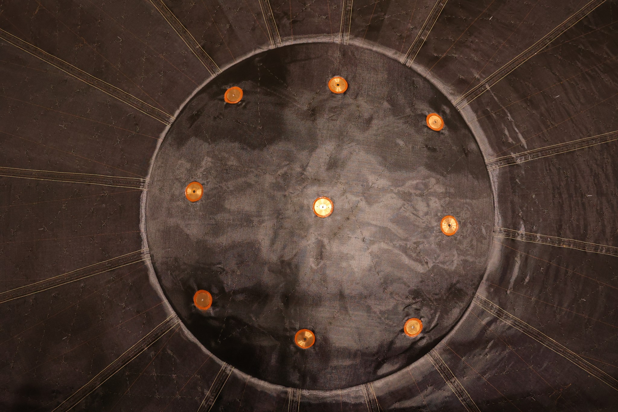 A closeup shot of one side of the spacecraft shows a circular panel with evenly spaced orange circles around the edge.