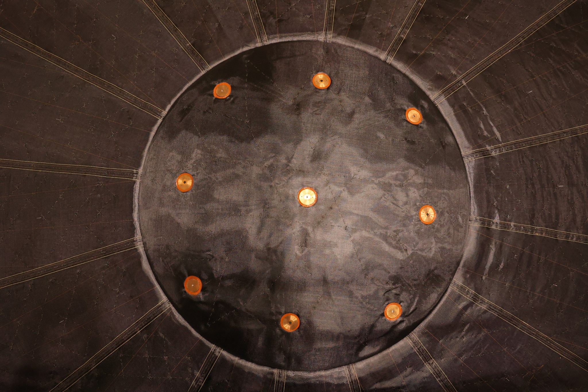 A closeup shot of one side of the spacecraft shows a circular panel with evenly spaced orange circles around the edge.