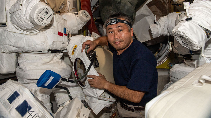 Astronaut Koichi Wakata works on spacesuits, also known as Extra-vehicular Mobility Units (EMUs), located in the space station's Quest airlock.