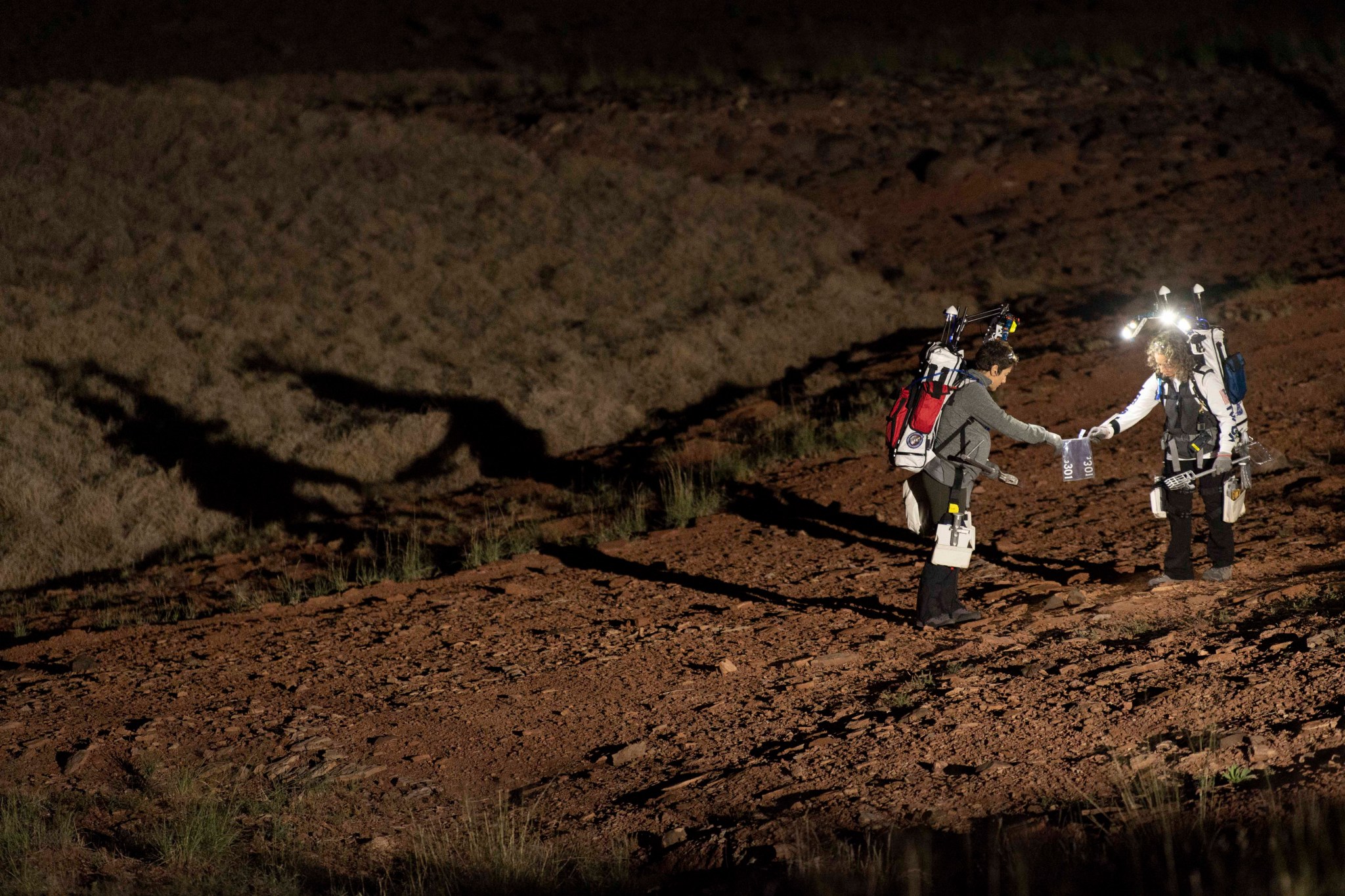 D-RATS crew members Jessica Meir and Tamra George collect a sample during a simulated moonwalk. 