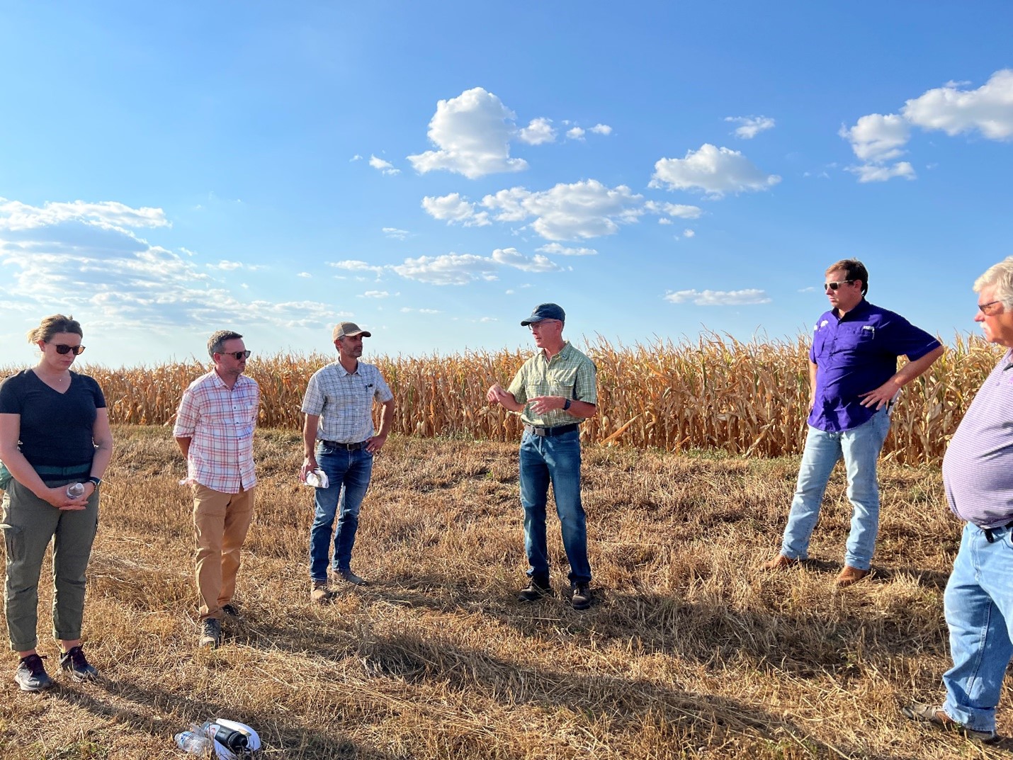 A group of men stand in a semi-circle in a field in Kansas.