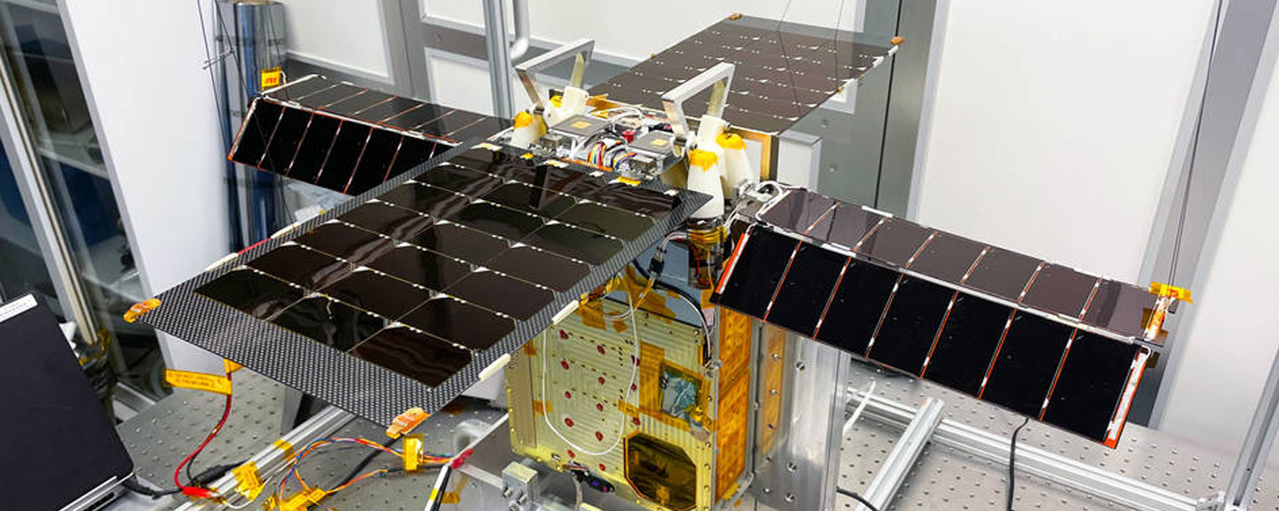The solar-powered small satellite is shown here with its for solar arrays extended in a Georgia Tech clean room.