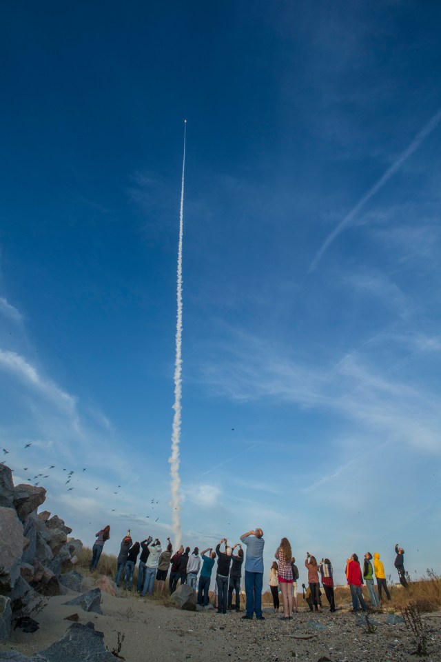 A group students watches a sounding rocket launch into the sky.