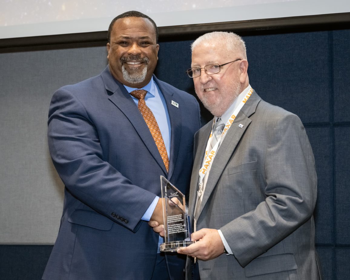 Two men accept the Neil Armstrong Space Flight Achievement Award and pose for a photo.