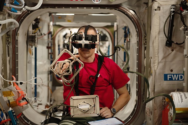image of an astronaut wearing a headset and hand grasping tools while working on an experiment