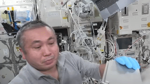 gif video of astronaut holding up experiment hardware