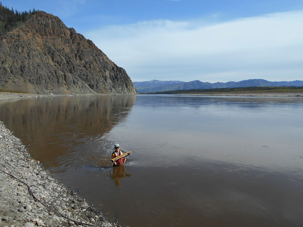 USGS hydrologist Heather Best makes a wading stream measurement at a gauge monitoring station in Alaska