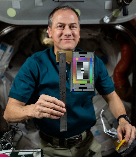 image of an astronaut holding up a color block chart as part of an archeological experiment
