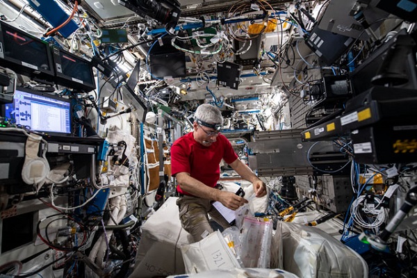image of an astronaut surrounded by floating storage boxes inside the space station laboratory
